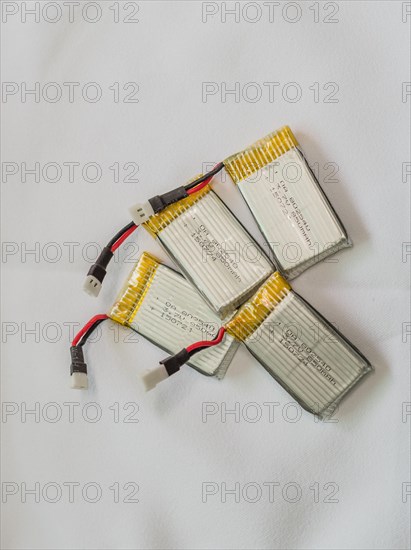 Several lithium polymer batteries with connectors and yellow tape on a white surface, in South Korea