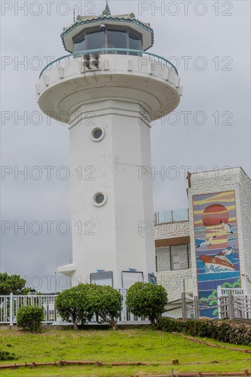 White lighthouse with a beacon on top, surrounded by trees and a wall mural, in Ulsan, South Korea, Asia