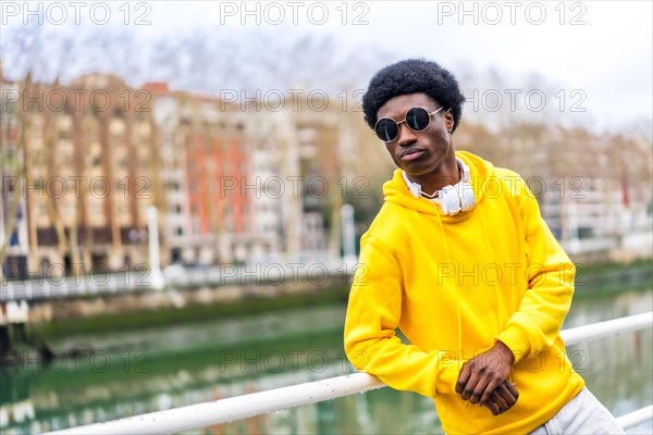 Portrait with copy space of a confident cool african young man wearing sunglasses next to an urban river in the city