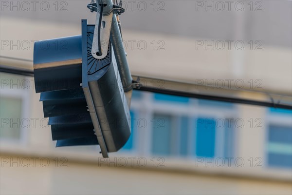 Bottom view of traffic light hanging from metal support with building blurred in background in Daejeon, South Korea, Asia