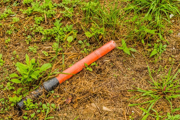 An orange tube on the grassy ground, symbolizing the issue of littering in natural areas, in South Korea