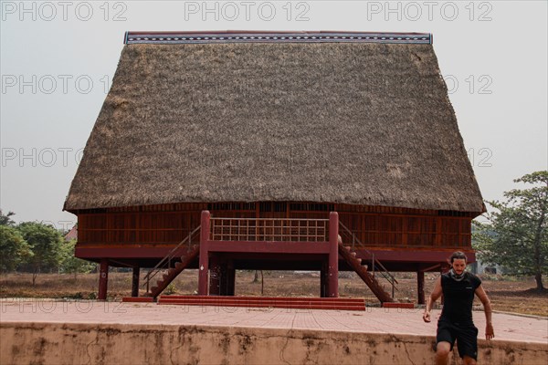 A tourist exploring a traditional architecture of a Bahnar ethnic stilt house or Rong House in Pleiku countryside, Vietnam, Asia