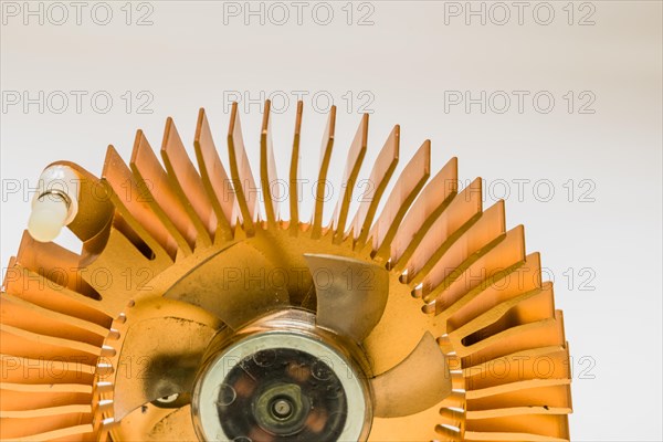 Closeup of round copper heat sink and plastic fan assembly on white background