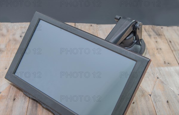 Front view of automobile navigation with attached mounting arm on wooden table with black background