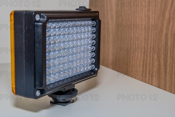 Closeup of LED continuous photographic light sitting on book shelf at home