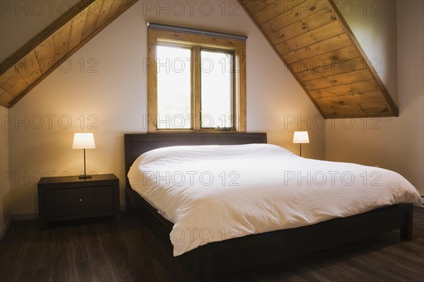 King size bed in master bedroom on upstairs floor inside contemporary style log home, Quebec, Canada, North America