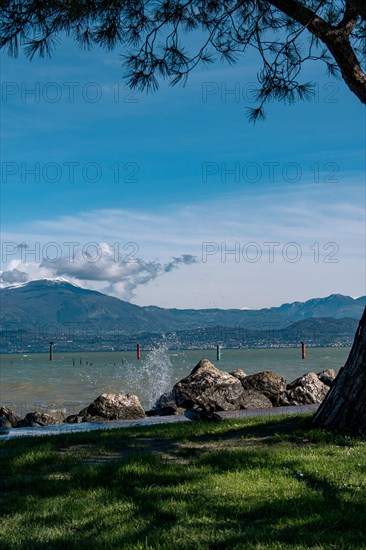 Splashing waves hitting rocks on the shore of Lake Garda, Sirmione, Lake Garda, Italy, Europe