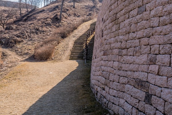 Section of mountain forest wall made of flat stones with wooden stairs for tourist on left side located in Boeun, South Korea, Asia