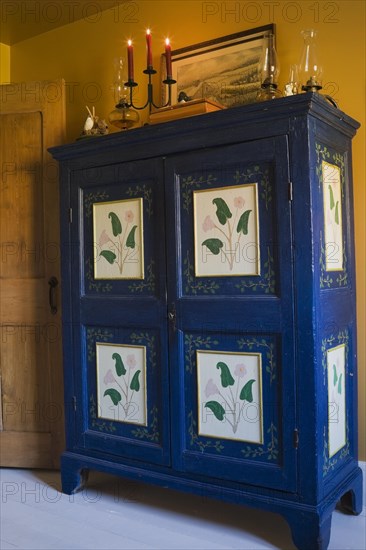 Antique blue and green painted wooden armoire in bedroom on upper floor inside old 1877 home, Quebec, Canada, North America