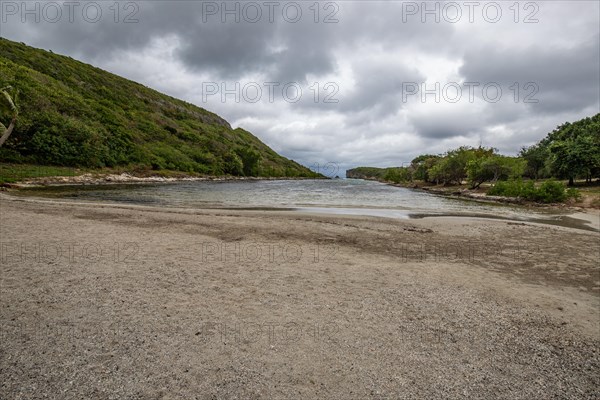 Rocky coast, long bay by the sea at sunset. Dangerous view of the Caribbean Sea. Tropical climate on a cloudy day in La Porte d'Enfer, Grande Terre, Guadeloupe, French Antilles, North America