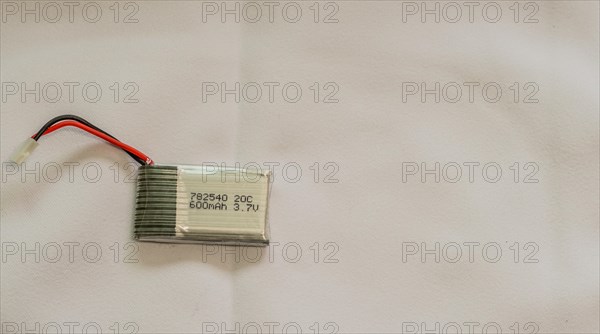 A lithium polymer battery with a label and wires on a white surface, in South Korea