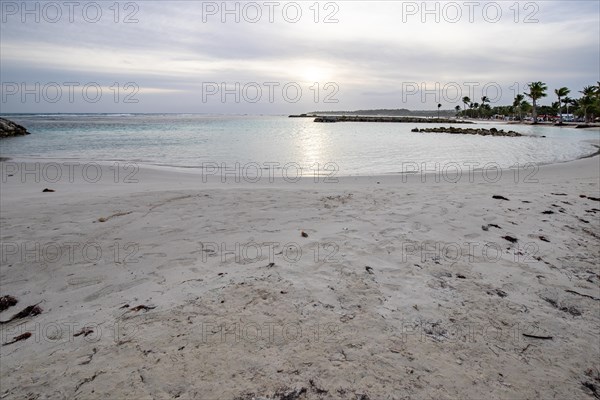 Caribbean dream beach with palm trees, white sandy beach and turquoise-coloured, crystal-clear water in the sea. Shallow bay on a cloudy day. Plage de Sainte Anne, Grande Terre, Guadeloupe, French Antilles, North America