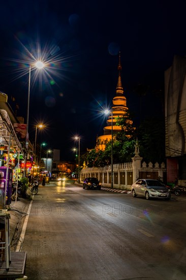 Quiet city street at night with temple in the background under a clear sky, in Chiang Mai, Thailand, Asia