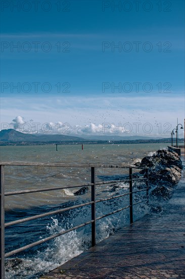 Splashing waves hitting rocks on the shore of Lake Garda, Sirmione, Lake Garda, Italy, Europe