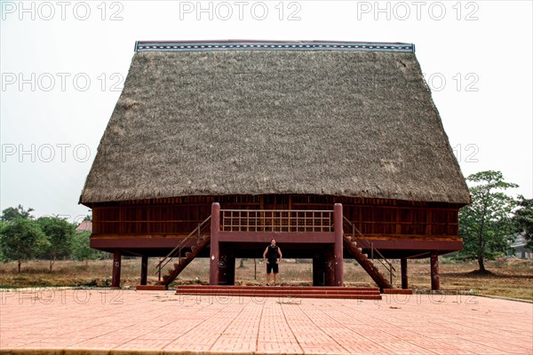 A tourist exploring a traditional architecture of a Bahnar ethnic stilt house or Rong House in Pleiku countryside, Vietnam, Asia