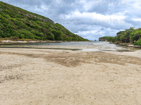 Rocky coast, long bay by the sea at sunset. Dangerous view of the Caribbean Sea. Tropical climate on a cloudy day in La Porte d'Enfer, Grande Terre, Guadeloupe, French Antilles, North America