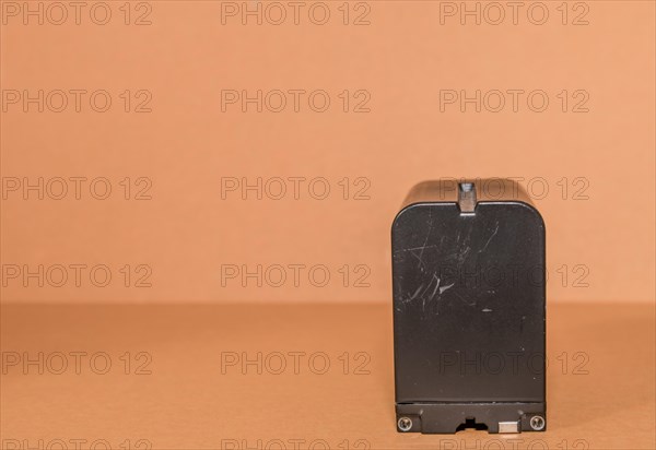 Closeup side view of used Lithium-ion battery on brown background