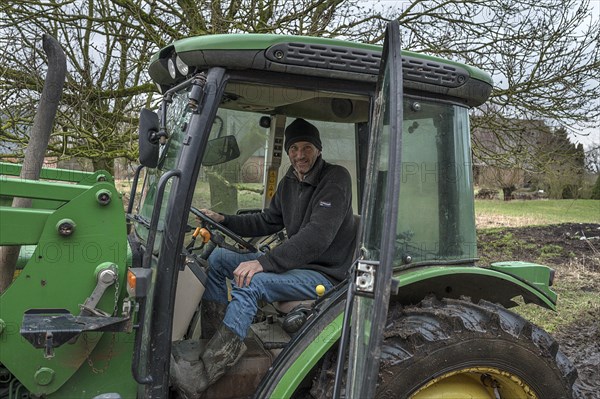 Young farmer in the tractor cab on his farm, Othenstorf, Mecklenburg-Vorpommern, Germany, Europe