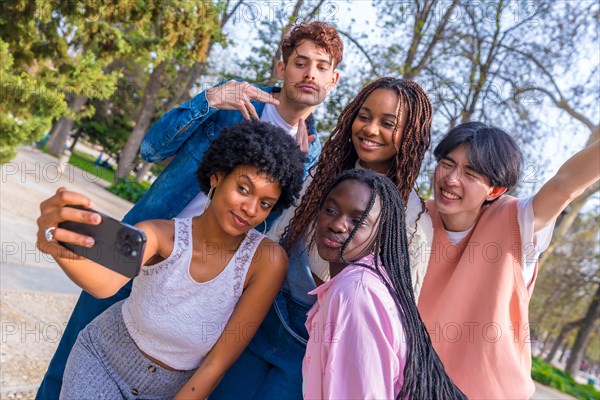 Dynamic shot of a group of cheerful multi-ethnic friends taking selfie together in a park