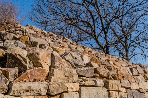 Closeup of section of mountain forest wall made of flat stones with tree and blue sky in background located in Boeun, South Korea, Asia