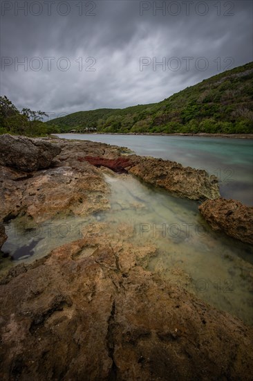 Rocky coast, long bay by the sea at sunset. Dangerous view of the Caribbean Sea. Tropical climate on a cloudy day in La Porte d'Enfer, Grande Terre, Guadeloupe, French Antilles, North America