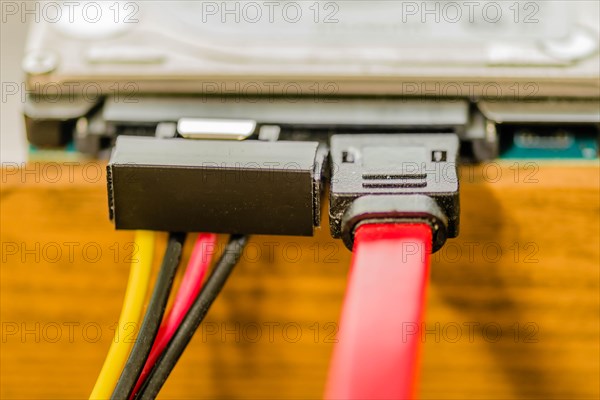 Closeup of sata cable plugged into computer hard disk on work bench. Left cable transfers power, right cable transfers data