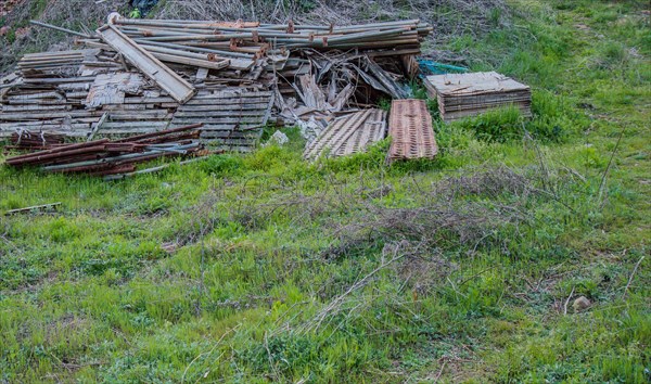 A large pile of wood and construction debris left on green grass, in South Korea