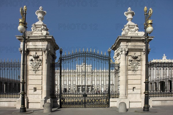 Baroque entrance gate of a castle with golden decorations under a clear blue sky PaMadrid Spain load