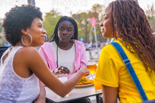 African young woman eating snacks in a sidewalk restaurant outdoors in a sunny spring day