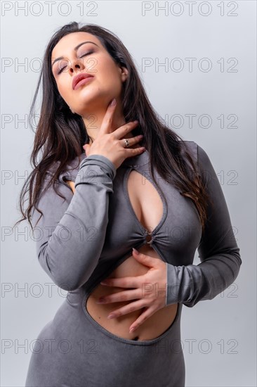 Studio photo with grey background of a cool model posing gesturing sensual on camera dressing long grey seductive dress