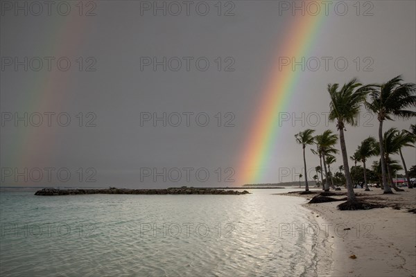 Caribbean dream beach with palm trees, white sandy beach and turquoise-coloured, crystal-clear water in the sea. Shallow bay with rainbow. Plage de Sainte Anne, Grande Terre, Guadeloupe, French Antilles, North America