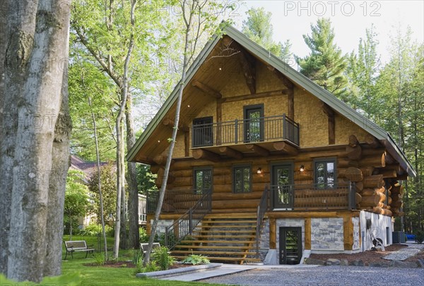 Luxurious two story Scandinavian style log cabin home facade in late spring, Quebec, Canada, North America