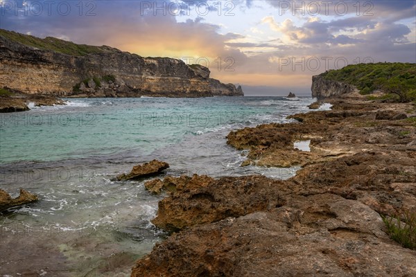 Rocky coast, long bay by the sea at sunset. Dangerous view of the Caribbean Sea. Tropical climate at sunset in La Porte d'Enfer, Grande Terre, Guadeloupe, French Antilles, North America