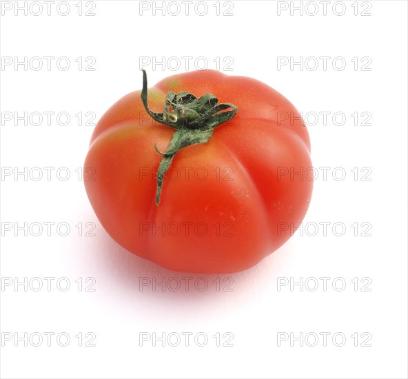 A ripe red tomato with a green stem isolated on a white background