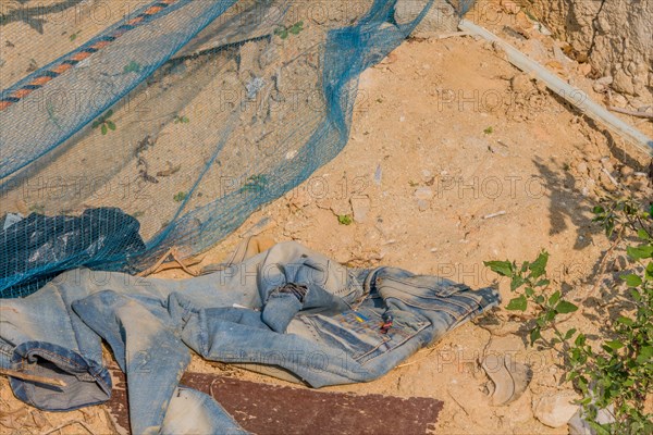 Discarded old clothes and a soil erosion net on dug up soil, showing environmental harm, in South Korea