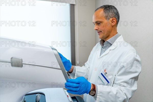 Side view of mature male ophthalmologist using an innovative laser machine to treat glaucoma