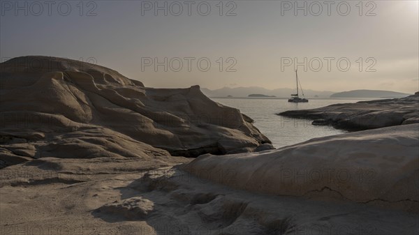 A sailing yacht behind the white rocks on the coast at Sarakinikoer, Milos, Cyclades, Greece, Europe