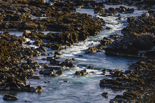 Rushing stream meanders through rocks to the Pjofafoss waterfall, Sudurland, Iceland, Europe