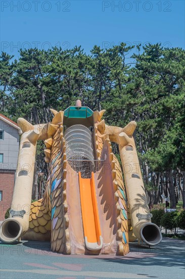 An inflatable slide with a dragon design at a playground surrounded by trees, in Ulsan, South Korea, Asia