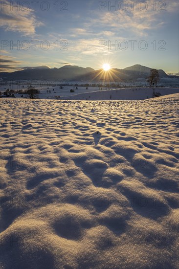 Sunrise over mountains in winter, snow, backlight, sunbeams, Alpine foothills, view of Benediktenwand, Rabenkopf, Jochberg, Kochler mountains, Bavaria, Germany, Europe