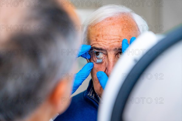 Ophthalmologist placing an eye opener to a senior man preparing him for a laser treatment for glaucoma