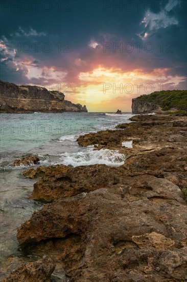 Rocky coast, long bay by the sea at sunset. Dangerous view of the Caribbean Sea. Tropical climate at sunset in La Porte d'Enfer, Grande Terre, Guadeloupe, French Antilles, North America