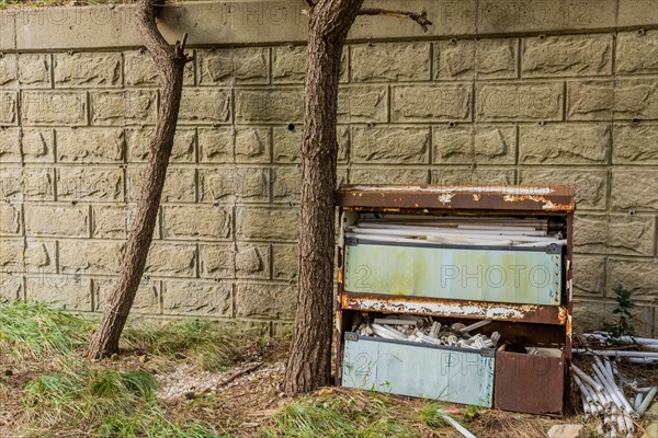 A decaying metal cabinet filled with expired light bulbs against a wall, in South Korea