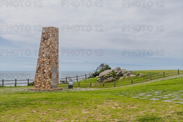 Stone monument in a grassy field with ocean in the background and cloudy skies, in Ulsan, South Korea, Asia