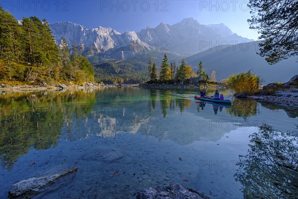 Canoeists on a mountain lake in front of steep mountains, reflection, evening light, autumn, Eibsee lake, view of Zugspitze, Bavaria, Germany, Europe