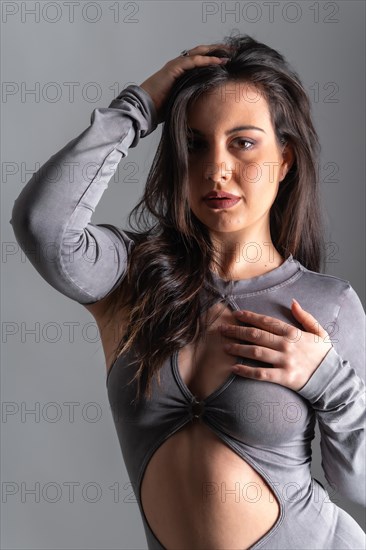 Studio photo with grey background of a beauty model posing with sensual gestures wearing long night dress