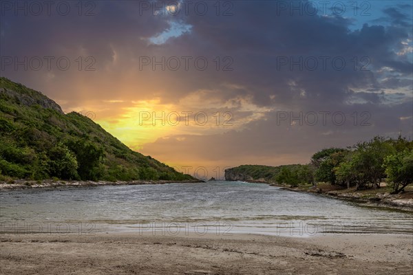 Rocky coast, long bay by the sea at sunset. Dangerous view of the Caribbean Sea. Tropical climate at sunset in La Porte d'Enfer, Grande Terre, Guadeloupe, French Antilles, North America