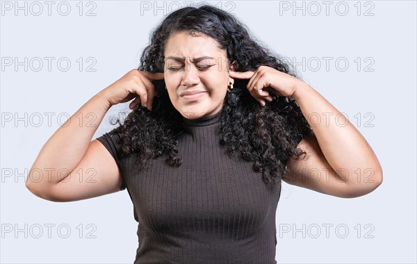 Frustrated young woman covering her ears ignoring something isolated. Displeased girl in glasses covering her ears