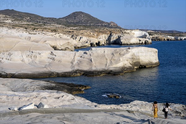 Two woman walking on the white rocks on the coast near Sarakinikoer, Milos, Cyclades, Greece, Europe