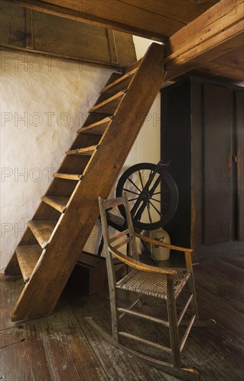 Antique rocking chair and spinning wheel next to Miller's stairs in master bedroom on upstairs floor leading to attic inside old 1785 home, Quebec, Canada, North America